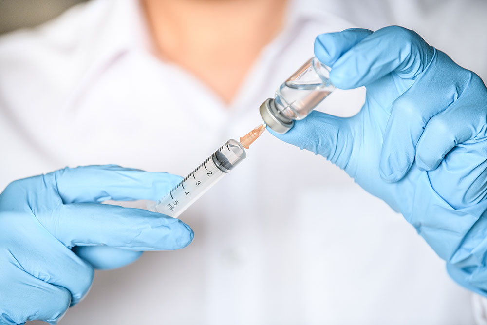 Buy Testosterone Online Doctor is Holding an Ampoule in Hands Wearing Medical Gloves